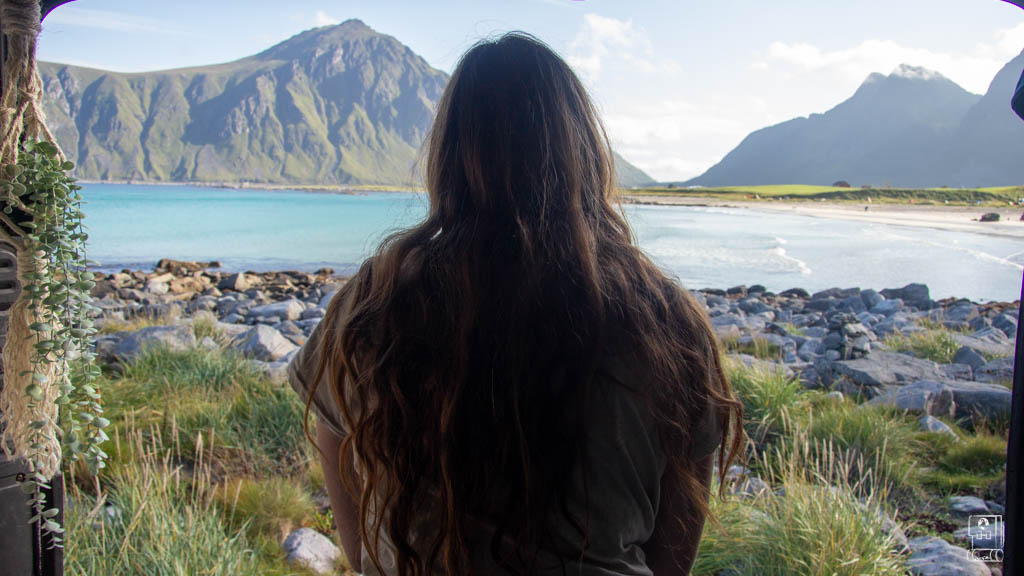 A woman enjoys a spectacular view of a sandy beach in Lofoten, representing the serene escapes available for accommodation in the region.