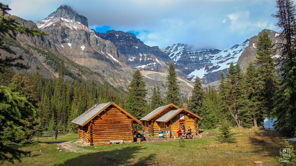 Elizabeth Parker Hut run by the Alpine Club of Canada sits in a colourful medow with a dramatic mountain backdrop
