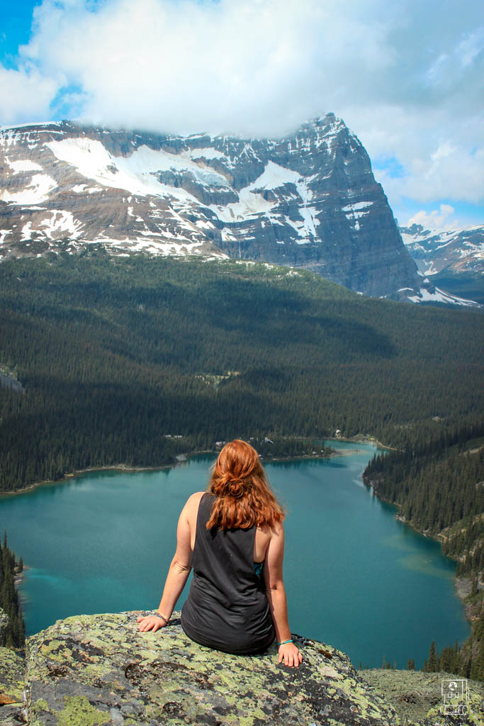 Female hiker enjoying Lake O'Hara hiking viewpoint, overlooking the iconic turquoise alpine lake with dramatic mountain backdrop in Yoho National Park, Canada