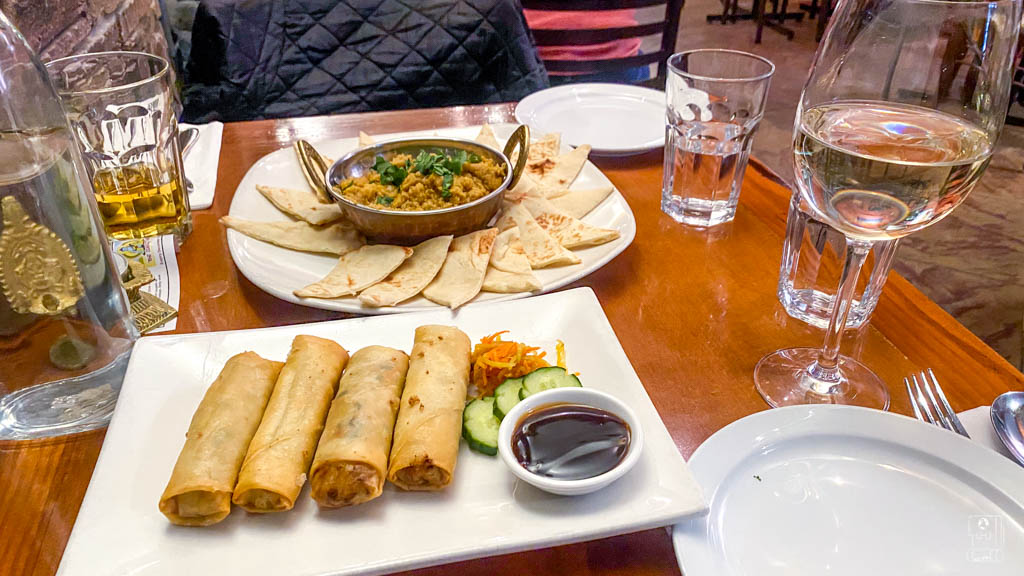 Fine dining experience at a leading Fernie restaurant with traditional Indian dishes including curry, naan bread, and spring rolls paired with wine service