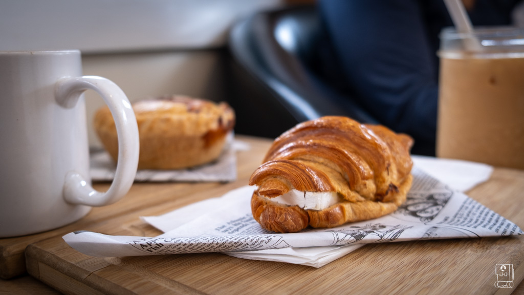 Freshly baked croissant with cheese filling at a top Fernie cafe, presented on newspaper-lined wooden serving board